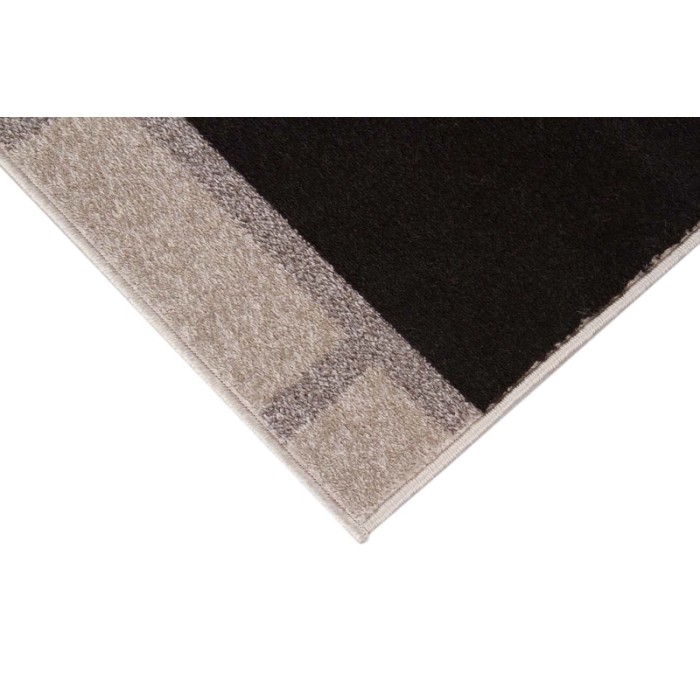 Dettaglio di un tappeto moderno con motivo geometrico in beige e nero.