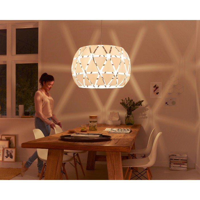 Lampada a sospensione bianca Philips Sandalwood, Ø 80cm, in soggiorno con tavolo da pranzo e donna.