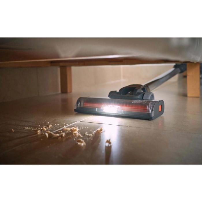 Aspirapolvere per pavimento in azione sotto un letto, con luce accesa.