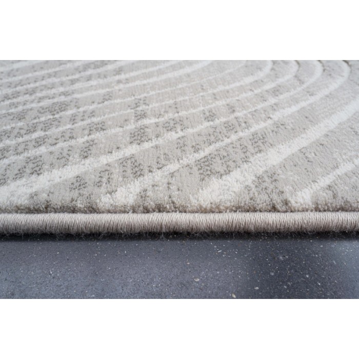 Dettaglio di un tappeto moderno con motivo astratto nei toni del beige e del bianco.