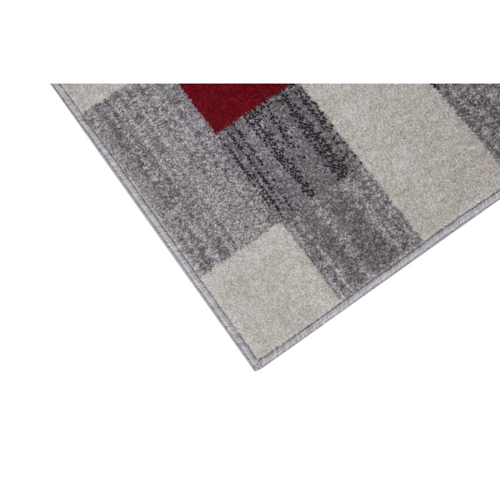 Dettaglio di un tappeto moderno con motivo geometrico nei toni del grigio e del rosso.