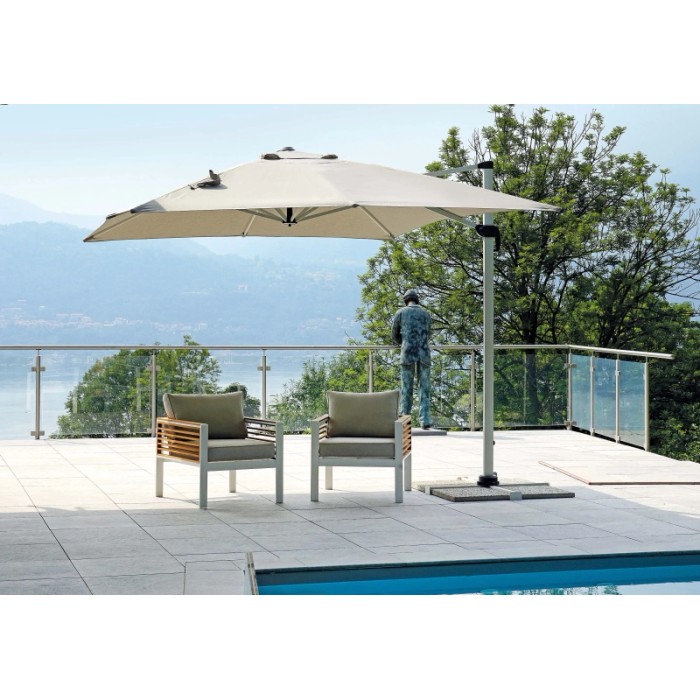 Ombrellone a braccio t.b.t. su terrazza con due poltrone e piscina sullo sfondo.