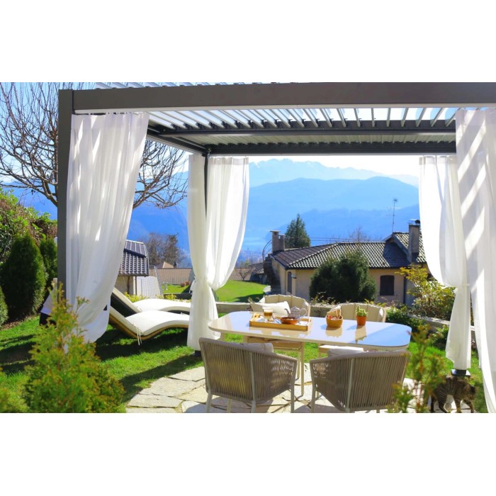 Patio con pergola, tende bianche, tavolo e sedie. Accessorio per la protezione solare.