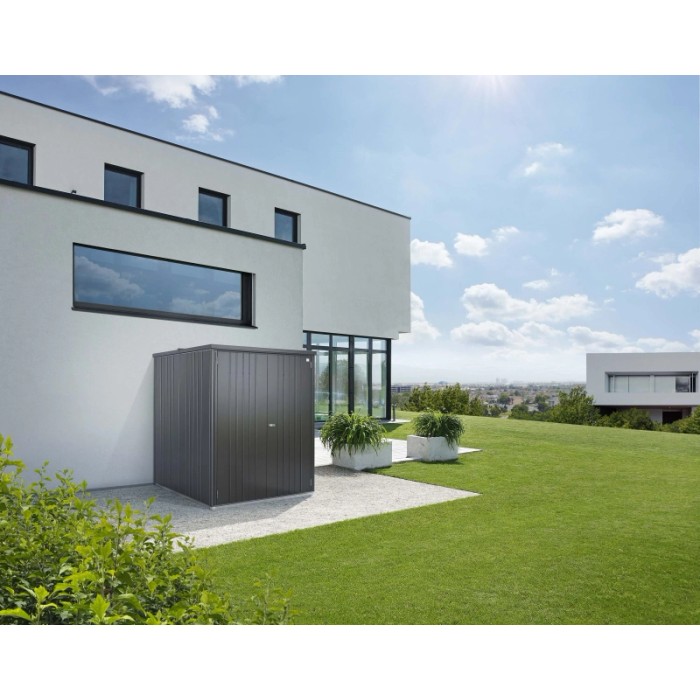 Armadio da esterno Biohort Large, grigio scuro metallizzato, davanti a casa moderna su prato.