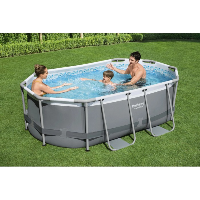 Piscina ovale con struttura metallica e famiglia in giardino. Piscina fuori terra.