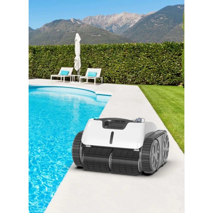Robot per piscina t.b.t. bianco a bordo piscina con piscina e giardino sullo sfondo.