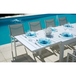 Tavolo da giardino bianco apparecchiato per cinque con piatti e bicchieri blu.