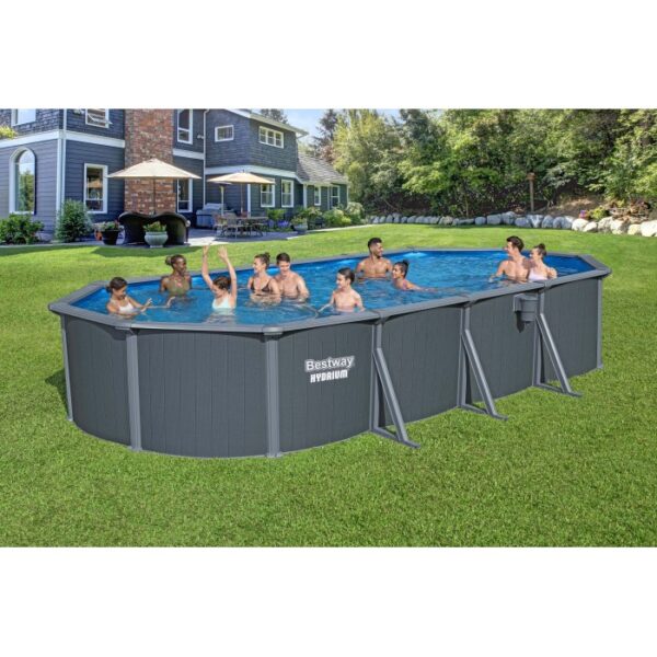 Piscina ovale con rivestimento grigio e bagnanti in giardino.