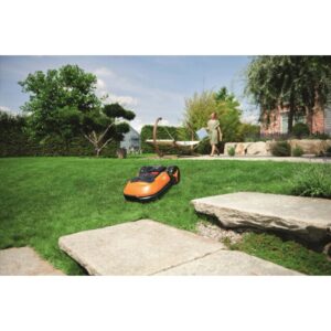 Robot tagliaerba Worx Landroid L1000 su prato in giardino. Donna sullo sfondo.