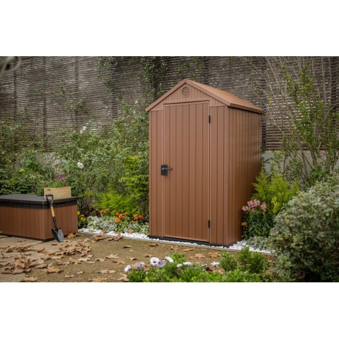 Casetta da giardino in plastica marrone in un ambiente da giardino. Ideale per riporre gli attrezzi da giardinaggio.