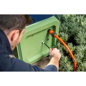 Uomo collega tubo arancione a pompa a pressione t.b.t. verde.