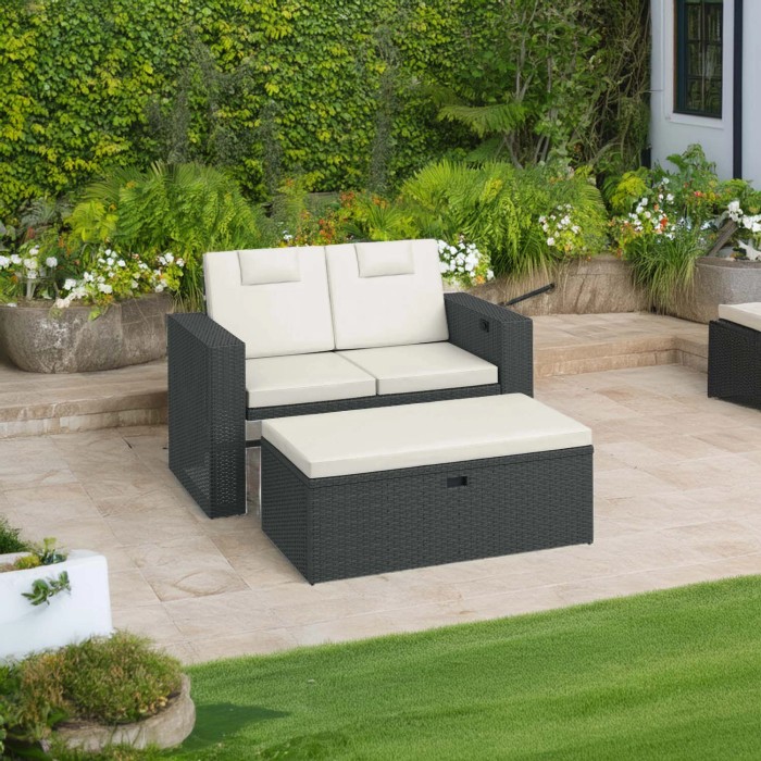 Salotto da giardino grigio t.b.t. con cuscini color crema e sgabello su un patio.
