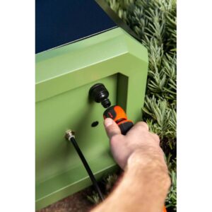 Pompa a pressione collegata all'armadietto da giardino verde.