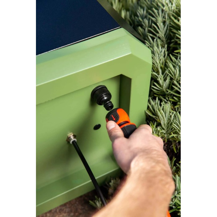 Pompa a pressione collegata all'armadietto da giardino verde.